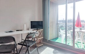 A room with a desk, a television, a chair, and a view of the city through large windows. - Lovely apartment in La Rochelle (La Rochelle)