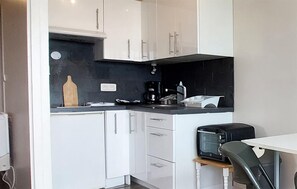 A compact kitchenette with white cabinets, a black countertop, a coffee maker, and a toaster. - Lovely apartment in La Rochelle (La Rochelle)