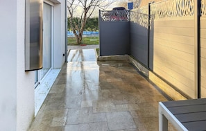 A narrow outdoor corridor with a tiled floor, a metal gate, and a wall with a decorative pattern. - Beautiful home in Fondettes with WiFi (Fondettes)