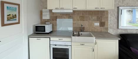 Una kitchenette compacta con microondas, horno, pileta y placares.