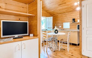 Ein Holzinterieur mit Fernseher, einem kleinen Tisch mit Stühlen und einer Küchenzeile inklusive Kaffeemaschine.