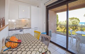 Eine moderne Küche mit weißen Schränken, einem Esstisch mit gemustertem Tischläufer und Blick auf einen Balkon mit Tisch und Stühlen.