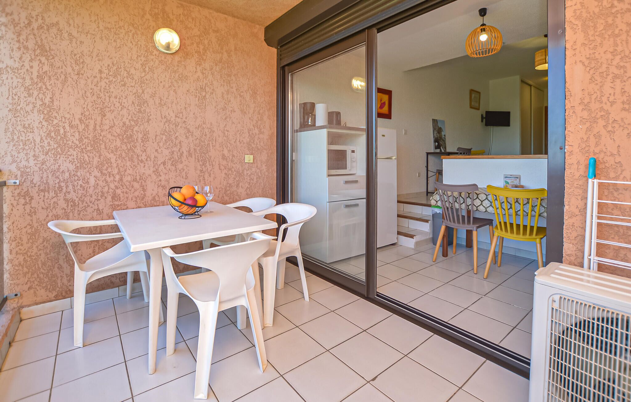 A dining area with a table and chairs, a fruit bowl, and a view into the kitchen.
