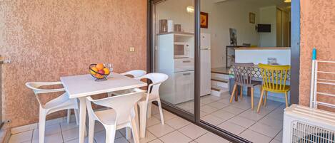 A dining area with a table and chairs, a fruit bowl, and a view into the kitchen.
