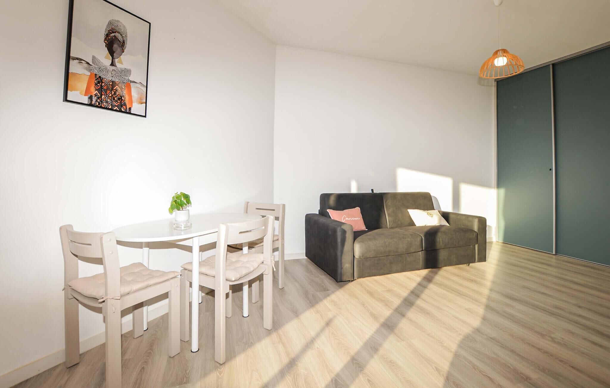 Un salon moderne comprenant un coin repas, un canapé et un luminaire suspendu.