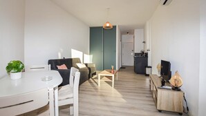 Ett modernt vardagsrum med en soffa, ett matbord och ett köksområde i bakgrunden.