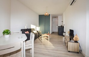 A modern living room with a sofa, a dining table, and a kitchen area in the background. - Nice apartment in Ste Lucie De Moriani (Ste Lucie De Moriani)