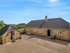 Une maison à deux étages, avec un toit en tuiles, une façade en briques et une allée pavée.