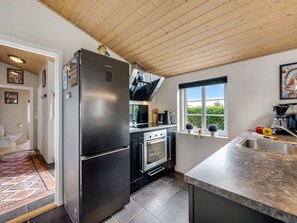 Eine moderne Küche mit einem Edelstahl-Kühlschrank, einem eingebauten Ofen und einem Fenster mit Blick auf Grünflächen.