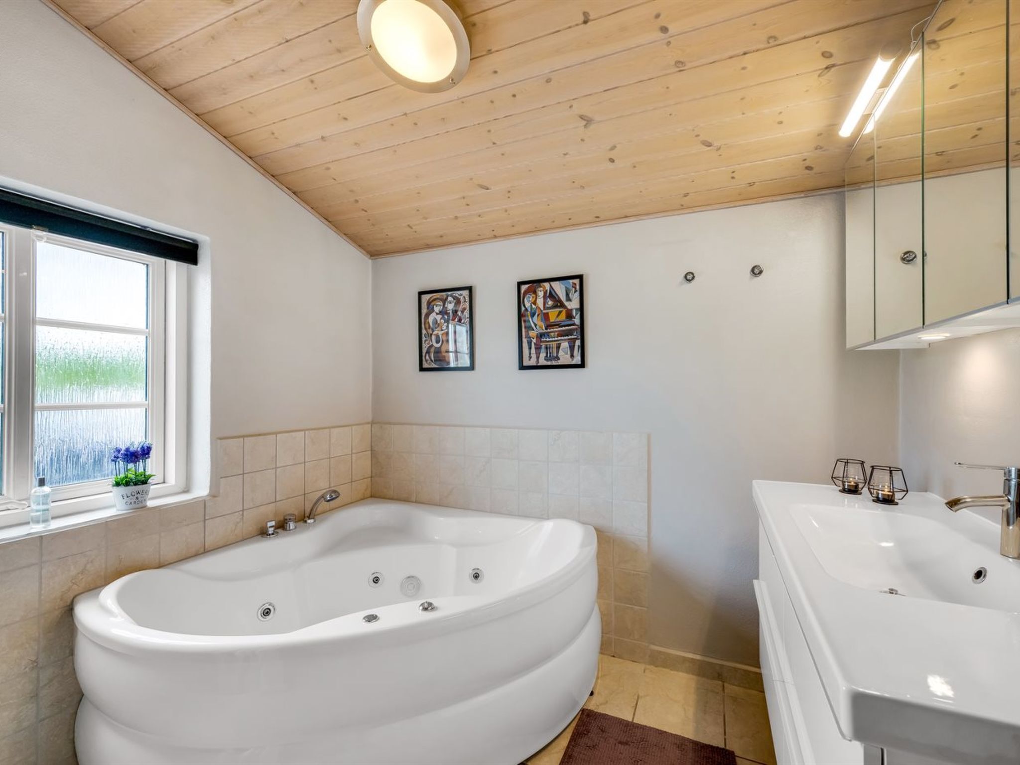 A modern bathroom with a freestanding bathtub, a double sink vanity, and two framed artworks on the wall.