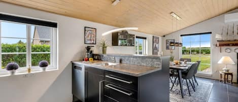 A modern kitchen with a central island, black cabinetry, and a view of the outdoors.