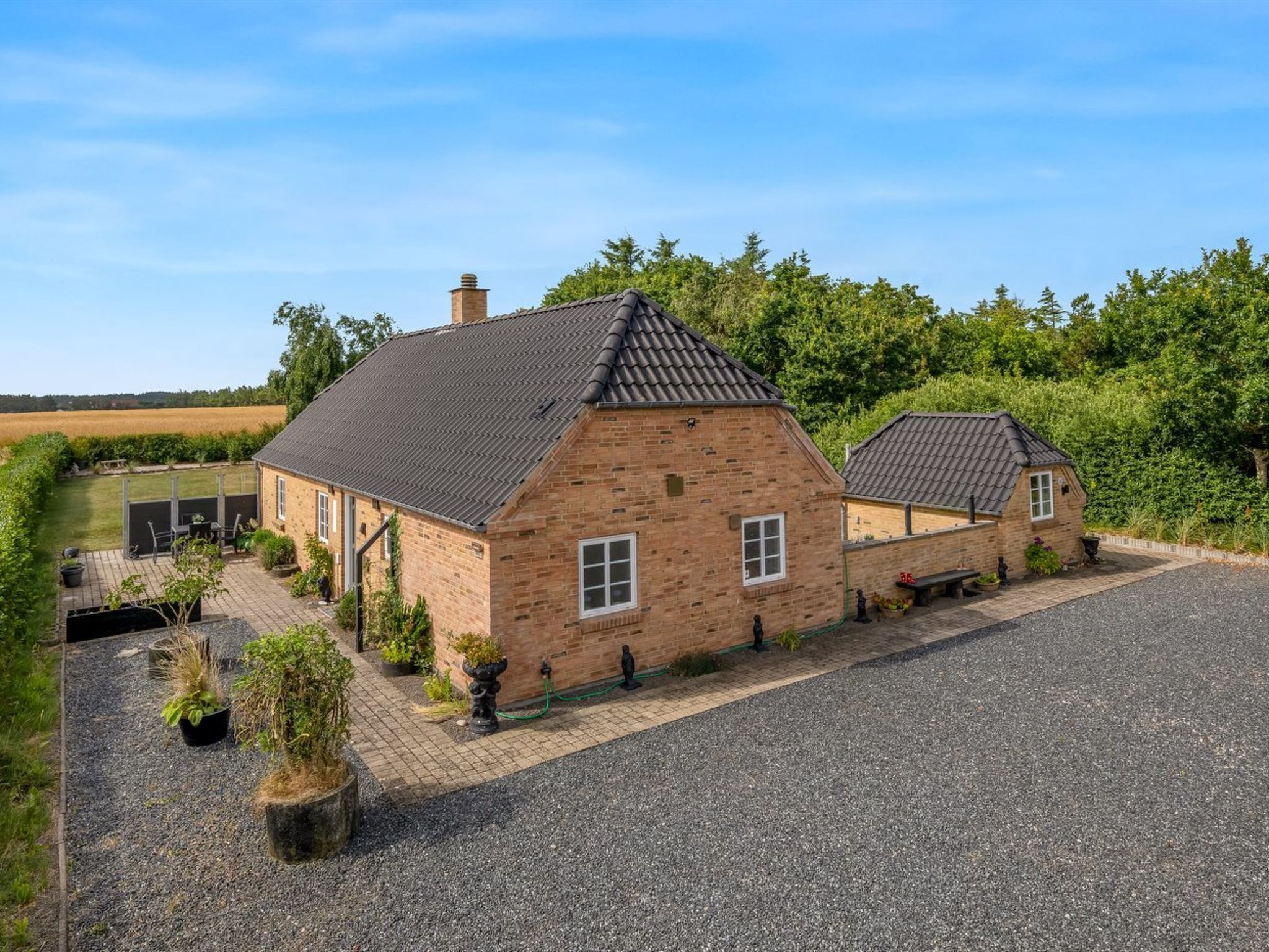 A brick house with a gravel driveway and a garden.