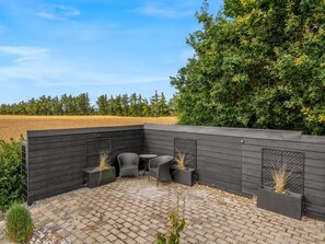 En uteplats med ett svart staket, två fåtöljer i rotting och ett litet bord.