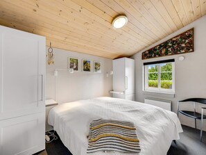 A bedroom with a large bed, a window with a view, and a ceiling with wooden beams. - "Meindor" - 450m to the fjord by Interhome (Ulfborg)