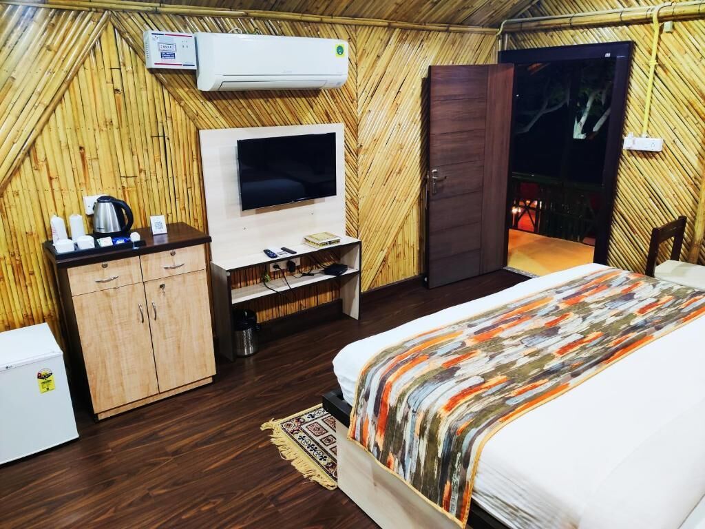 Quarto com cama, televisão, guarda-roupa e uma kitchenette.