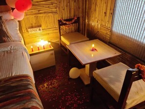 Una habitación con una cama, una mesa con velas, una silla y una ventana con persianas.