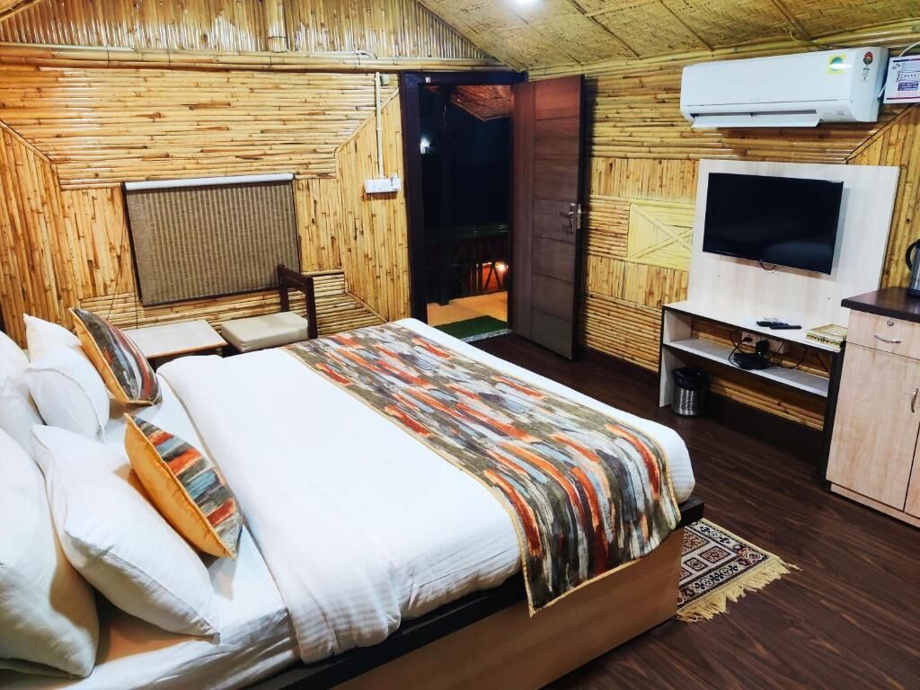 Una habitación con paneles de madera, una cama, un televisor y una puerta que da al exterior.
