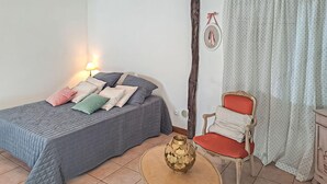 A bedroom with a bed, pillows, a chair, a small table, a lamp, and curtains. - Beautiful apartment in Puy-L'Evêque (Puy-L'Evêque)