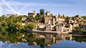 A historic town with buildings reflecting on calm water, surrounded by greenery. - Beautiful apartment in Puy-L'Evêque (Puy-L'Evêque)