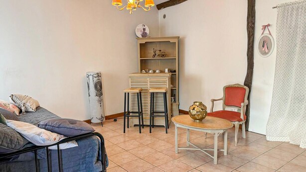 A room with a bed, a table with chairs, a bookshelf, and a chair with a red cushion. - Beautiful apartment in Puy-L'Evêque (Puy-L'Evêque)