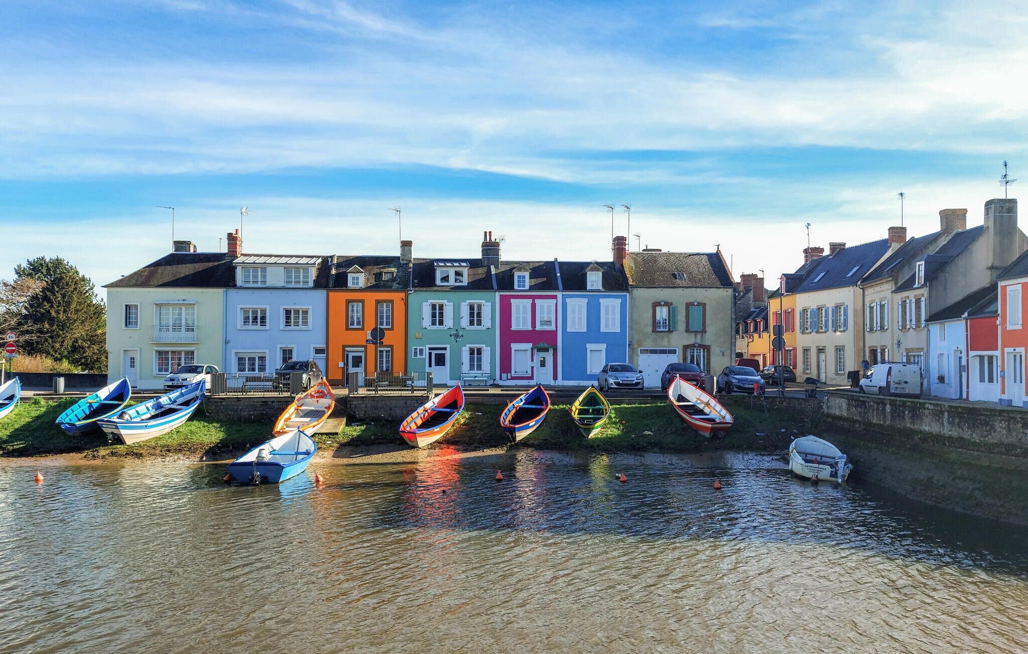 A canal with colorful boats docked and houses along the water's edge.