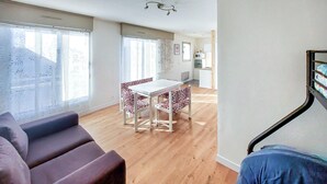 A modern living room with a sofa, a dining table with chairs, and a staircase. - Awesome apartment in Dunkerque (Dunkerque)