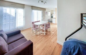 Ein modernes Wohnzimmer mit einer Couch, einem Esstisch mit Stühlen und einer Treppe.