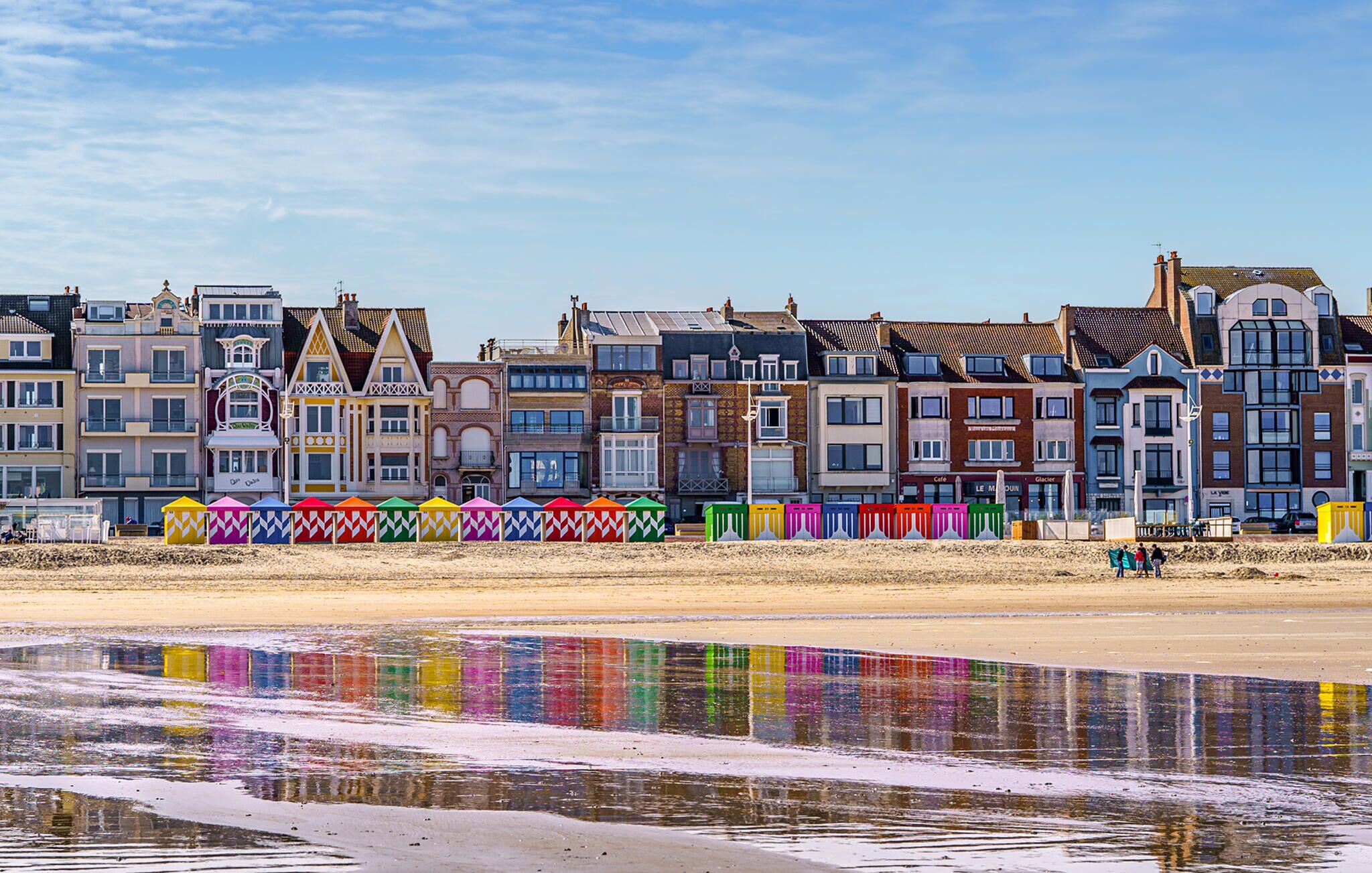 A row of colorful beach houses with a sandy beach in the foreground.