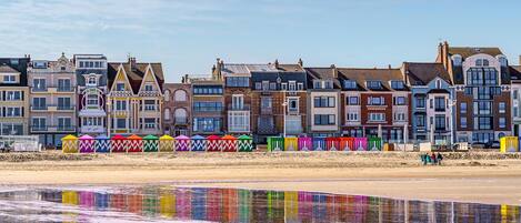 A row of colorful beach houses with a sandy beach in the foreground.