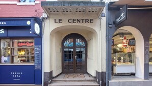 Ingången till ”LE CENTRE” består av en valvformad stenöppning och en glasdörr.