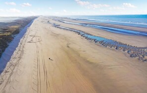 Eine Küstenlandschaft mit Sandstrand, Felsenmole und blauem Himmel.