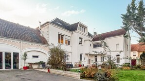 En bostadsbyggnad med många fönster, ett garage och en välskött trädgård.