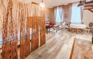 A room with a dining table, chairs, a sofa, and a decorative wall panel. - Lovely home in Huby Saint Leu with WiFi (Huby Saint Leu)