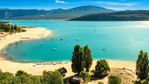 Eine Küstenlandschaft mit Strand, Booten und Bergen im Hintergrund.