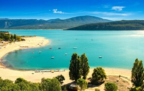 A coastal landscape with a beach, boats, and mountains in the background. - Appart. dans maison de village (Montagnac-Montpezat)