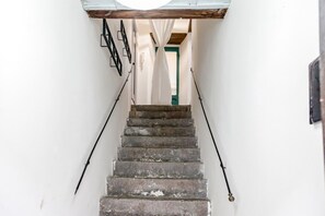 A staircase with a handrail on each side, leading to a door with a green frame.