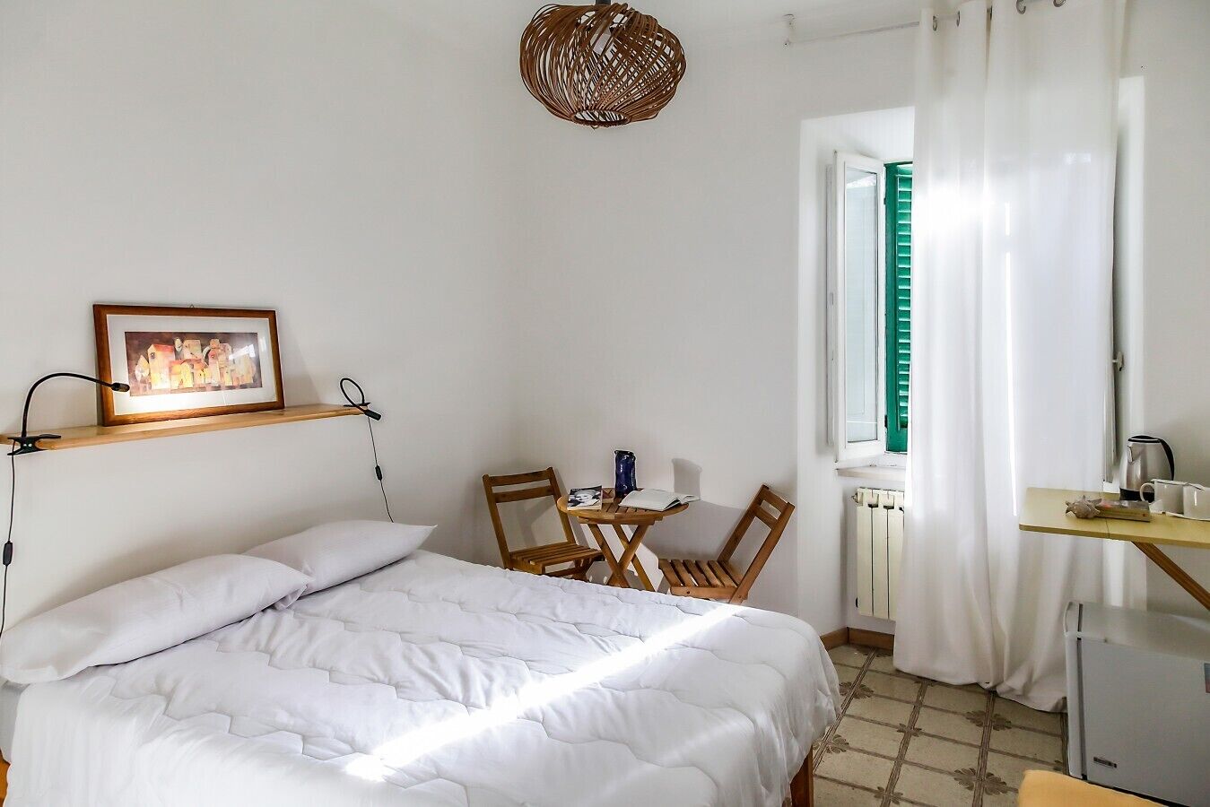 Ein Schlafzimmer mit einem Bett, einem Schreibtisch, einem Stuhl, einem Bilderrahmen und einem Fenster mit Vorhängen.
