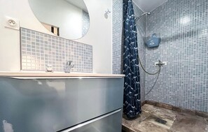 A bathroom with a sink, mirror, shower, and tiled walls. - Nice home in Miramas with outdoor swimming pool (Miramas)
