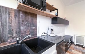 A modern kitchen with a black sink, a coffee machine, and wooden shelves. - Nice home in Miramas with outdoor swimming pool (Miramas)