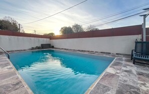 A rectangular swimming pool with a tiled deck, surrounded by a low brick wall and a white fence. - Nice home in Miramas with outdoor swimming pool (Miramas)