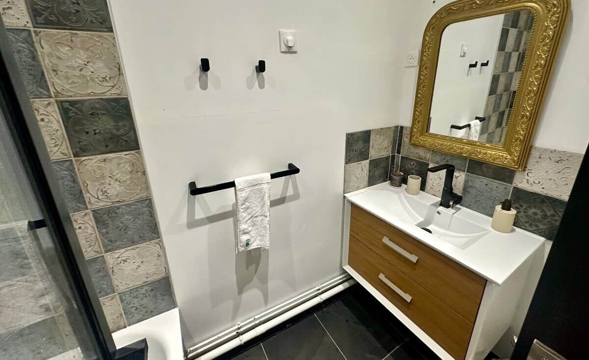 A bathroom with a shower, a sink, a mirror, and a towel rack.