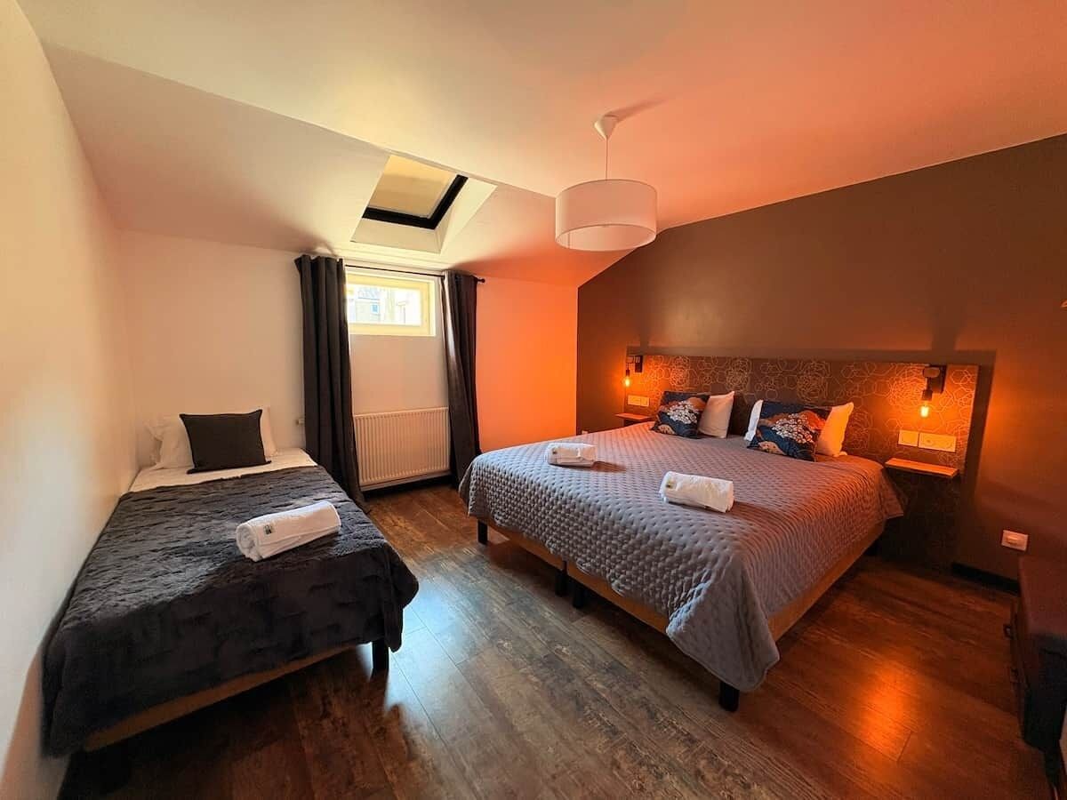 Habitación de hotel con dos camas, tragaluz, ventana grande y lámpara moderna.