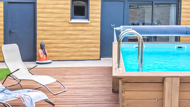 Ein Poolbereich mit Holzterrasse, Whirlpool und Liegestühlen.