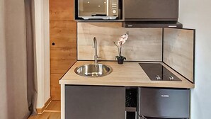 Eine kleine Küche mit Mikrowelle, Spüle und einem Hängeschrank.