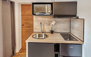 Eine kleine Küche mit Mikrowelle, Spüle und einem Hängeschrank.