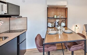 A modern kitchen with a dining area, including a table set for two with plates, glasses, and cutlery.