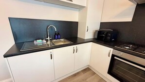Eine moderne Küche mit schwarzem Arbeitsplatz, Spüle aus Edelstahl und eingebautem Backofen.