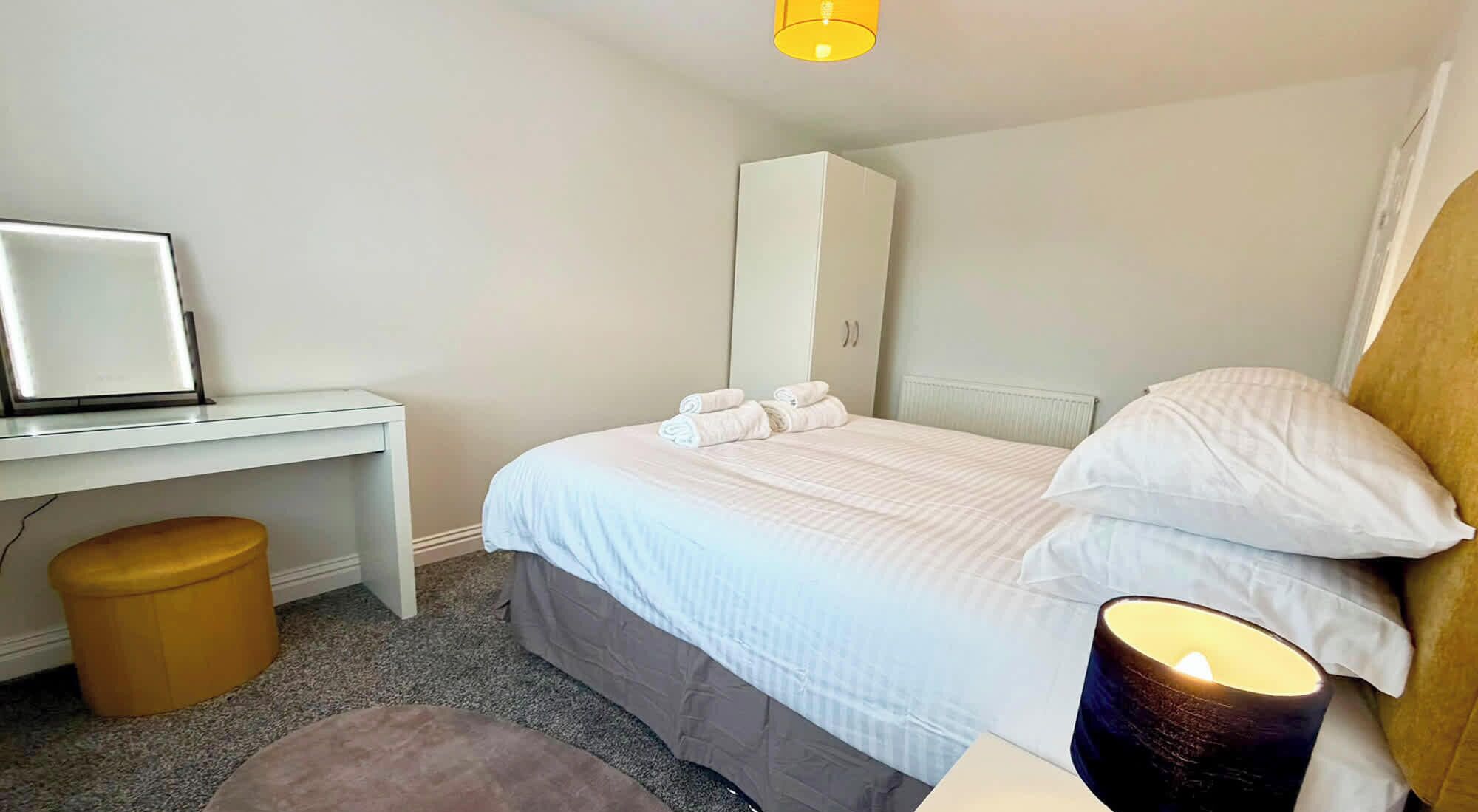 Ein Hotelzimmer mit Bett, Schreibtisch, Stuhl, Lampe und Heizkörper.
