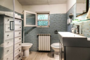 Un baño con inodoro, bidé, lavabo, espejo y ventana.