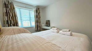 Una habitación de hotel con una cama, un escritorio y un ventanal con cortinas.